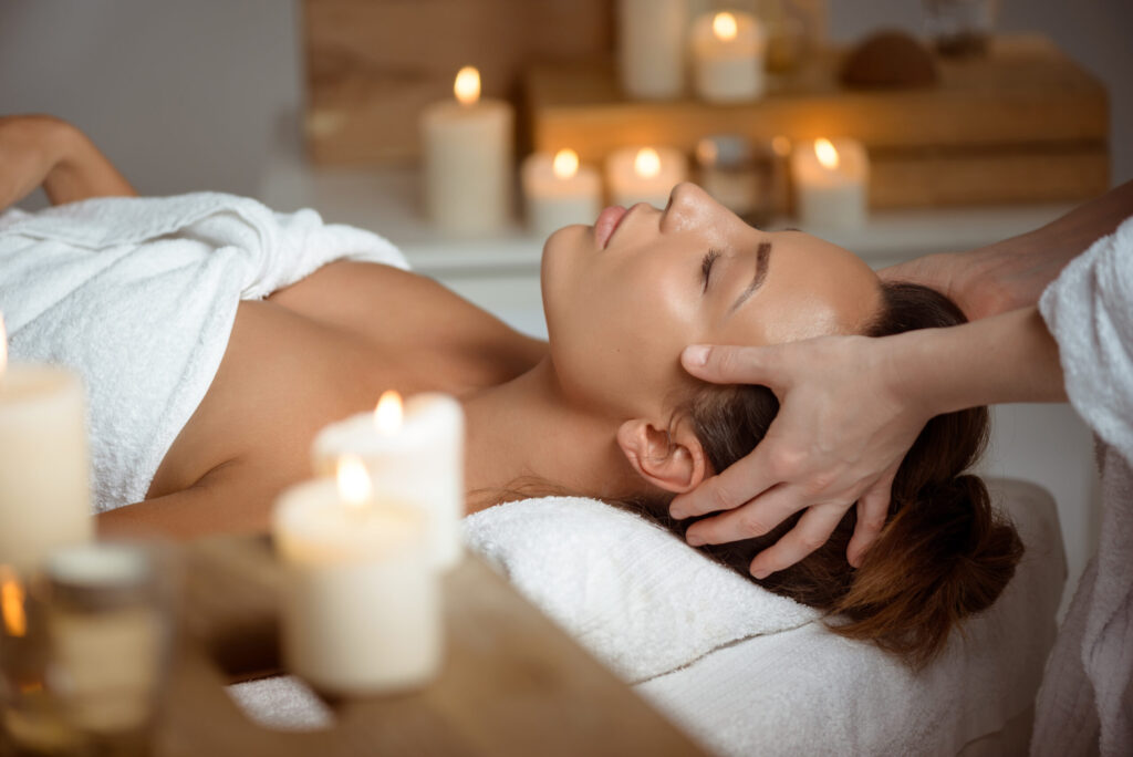 Young beautiful girl having face massage relaxing in spa salon.